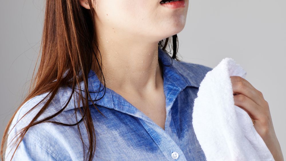 暑さでシャツに汗染みができている女性の首元