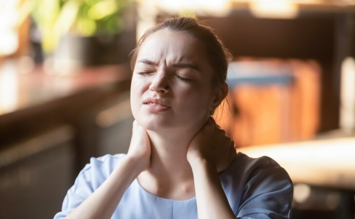首に手を当ててつらそうにしている女性