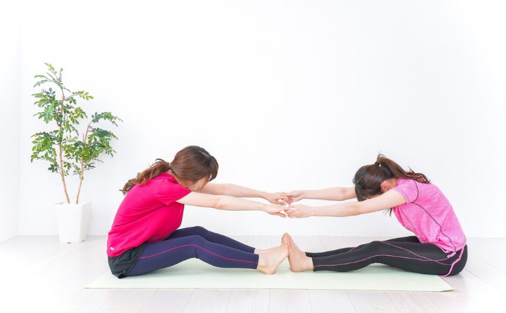 前屈のパートナーストレッチをしているふたりの女性