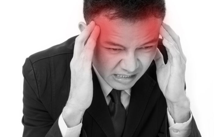 頭痛で頭をおさえている男性