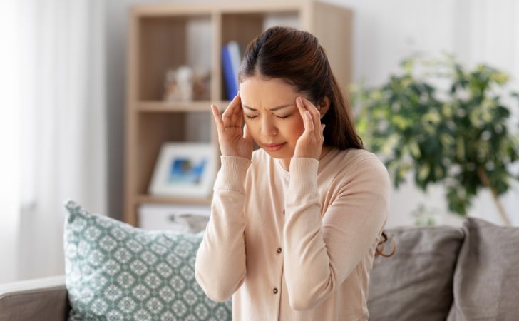 頭痛でこめかみを抑える女性
