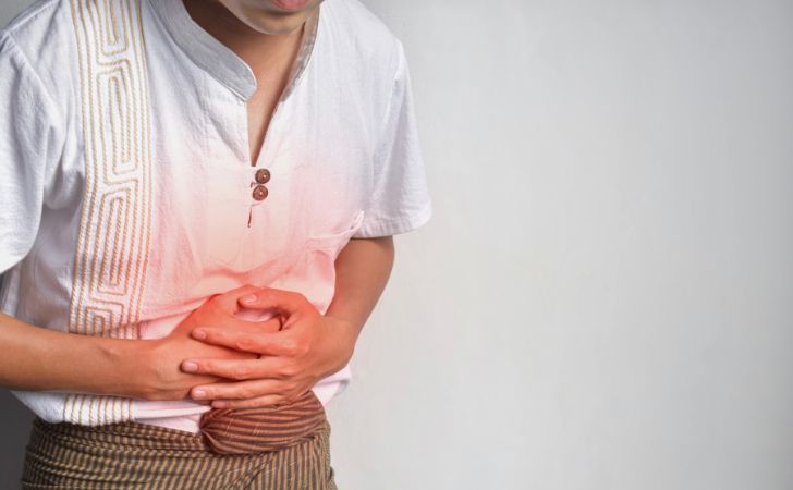 腹痛でお腹をおさえている男性