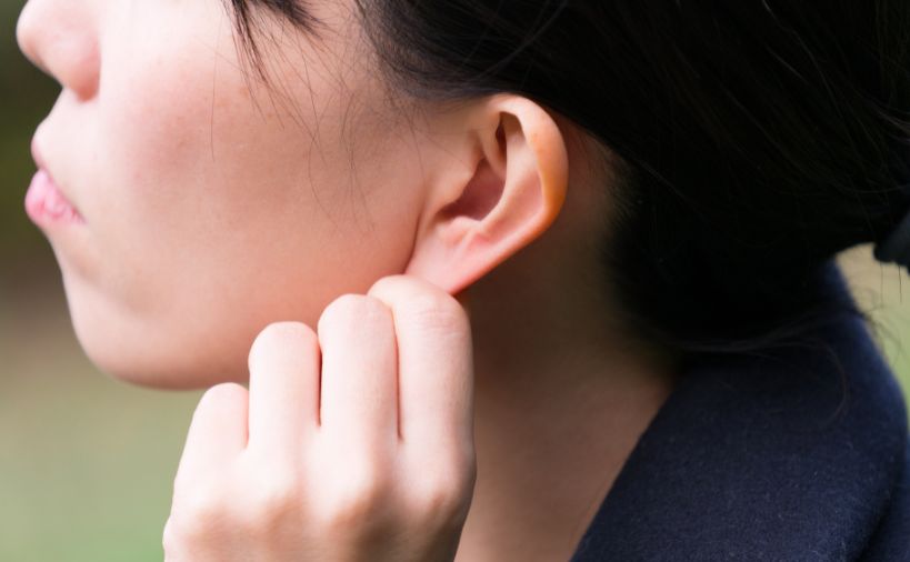 耳のセルフマッサージをしている女性