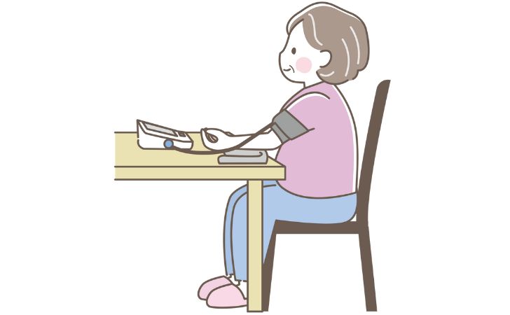 椅子に腰掛けて血圧を測定している女性