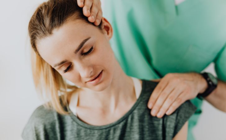 整体師に肩のストレッチを受けている女性