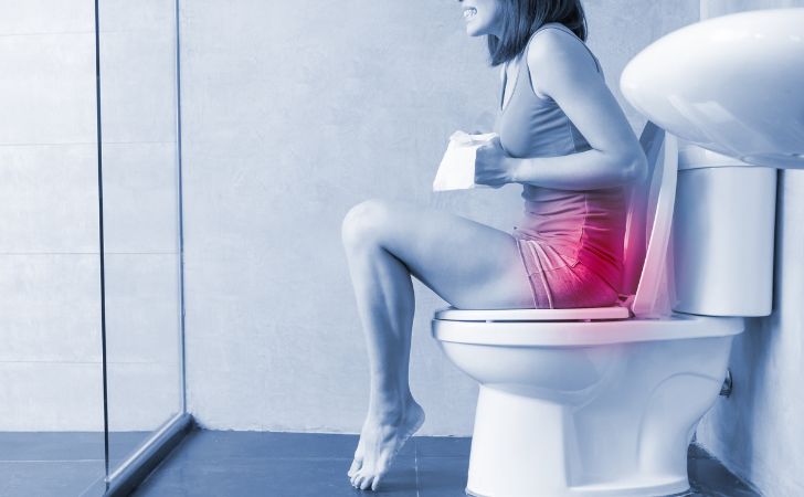 便座に座り痛みを感じている女性