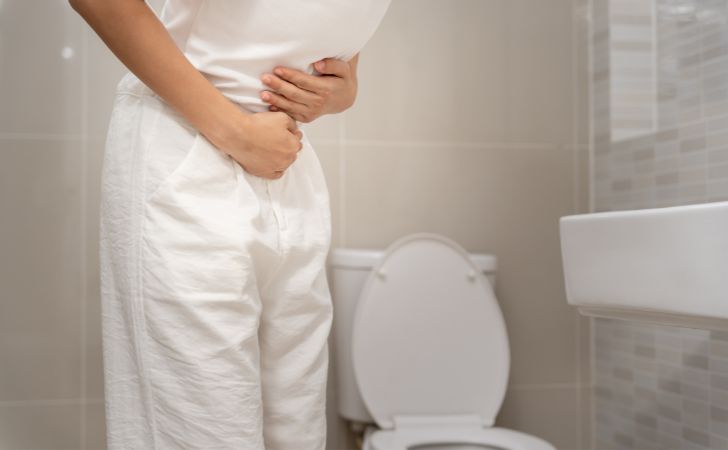 腹痛でお腹をおさえる女性