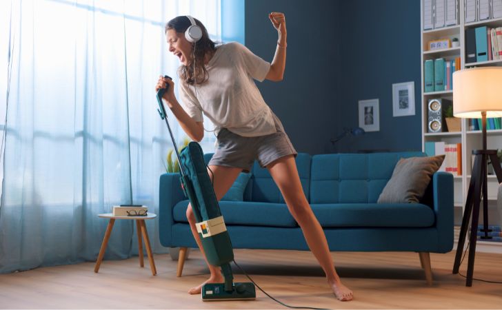 掃除機をマイクに見立てて熱唱している女性