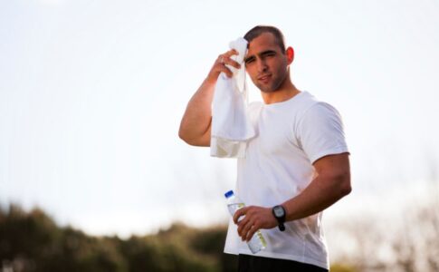 運動をして水分補給しつつ汗を拭く男性