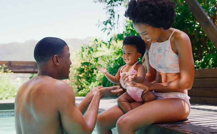 プールで黒人の夫婦が赤ちゃんをあやしている様子