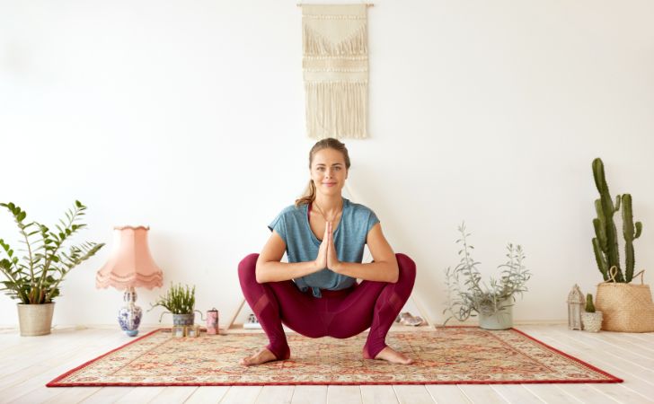 ヨガの花輪のポーズ(しゃがみ姿勢)をしている女性