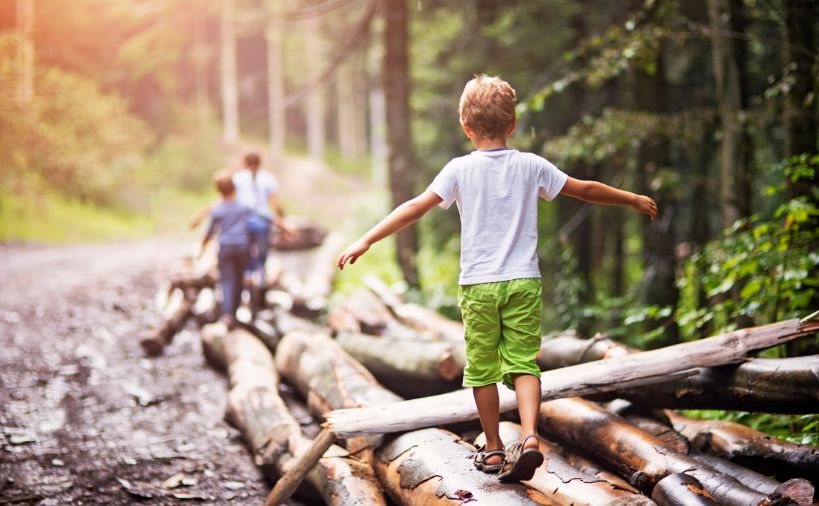 丸太の上をバランスをとりながら歩く少年